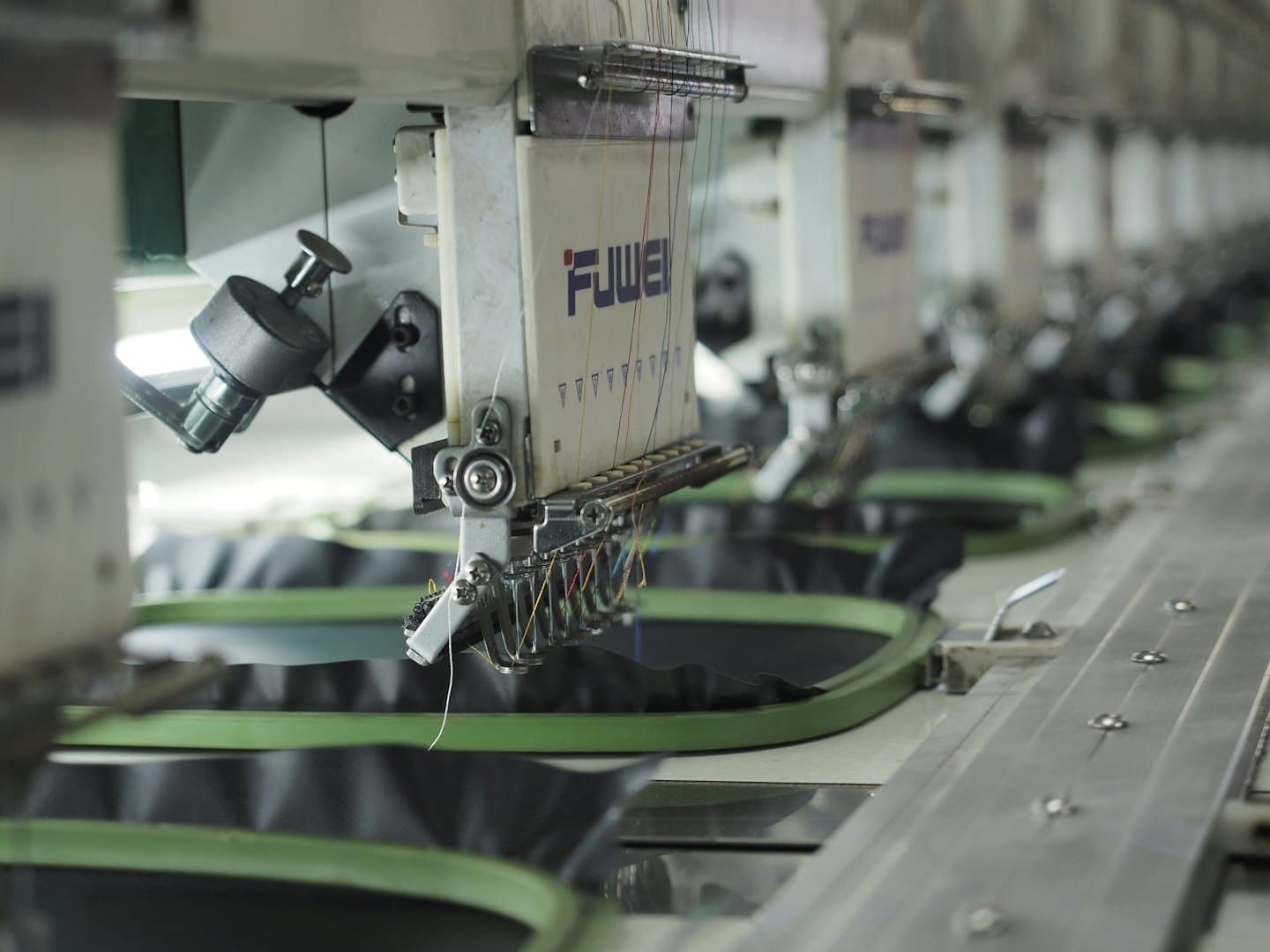 Industrial embroidery machines with colorful thread spools.